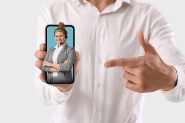 Man holding mobile phone with female business speaker on screen against white background