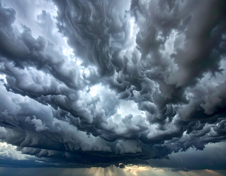 A breathtaking display of dark, turbulent mammatus clouds filling the sky, with dramatic sunrays piercing through. Captures nature's raw power and beauty.
