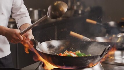 A chef skillfully cooks vegetables in a wok over an open flame, creating a dynamic culinary scene - Powered by Adobe