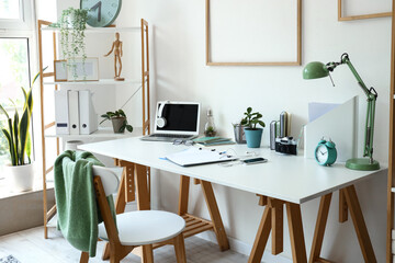 Interior of light office with workplace and shelving unit