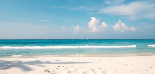 White sandy tropical beach with a backdrop of calm sea and a clear blue sky.