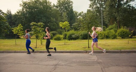 Women athletes in colorful sportswear run through city park