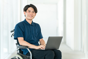 A young Asian man in a wheelchair using a computer (volunteer, fundraising, donation, charity, care, welfare)
