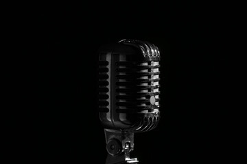 Fototapeta premium Vintage microphone on a stand classic audio equipment for broadcasting music and public speaking isolated on a dark background