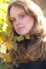 Portrait of a young woman in sunny autumn park