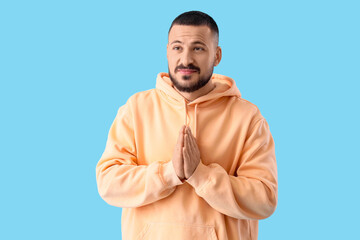 Apologetic young man on blue background