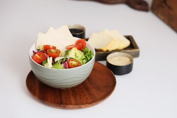 Bowl with tasty tofu and vegetables on table in kitchen