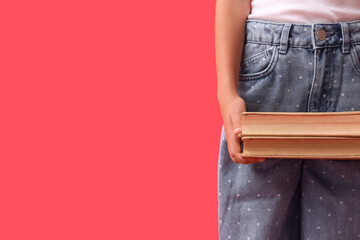 Cute little girl holding books on red background