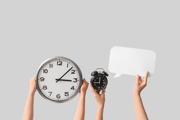 Female hands holding different clocks with blank speech cloud on grey background