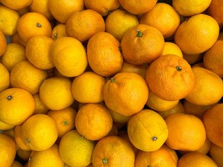 Close-up of a pile of fresh tangerines with vibrant orange skin, creating a bright and natural...