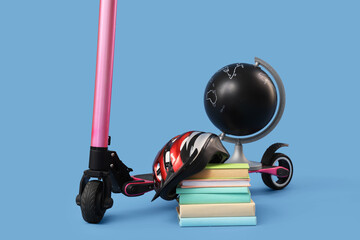 Modern electric scooter with helmet, globe and books on blue background, closeup