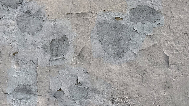 Close-up of a weathered wall with peeling paint and gray patches, showing rough texture and signs of aging and surface deterioration.