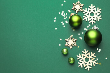 Beautiful Christmas composition baubles, decorative snowflakes and confetti on green background, flat lay. Space for text