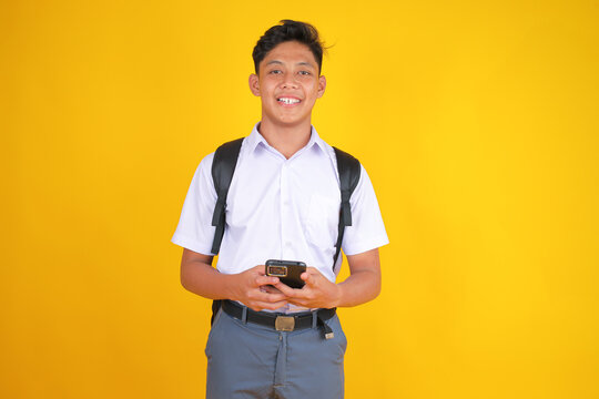 Smiling Student Using Phone Against Vibrant Yellow Backdrop