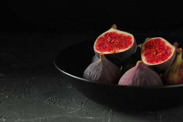 Bowl with fresh ripe figs on black background, closeup