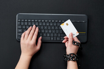Woman with metal chain holding credit card over keyboard, online shopping addiction concept