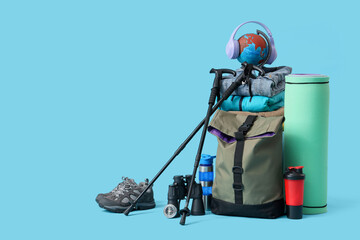 Walking poles, backpack and hiking equipment on blue background
