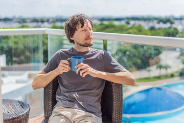 Obraz premium Man drinking coffee on the balcony in the morning. Concept of relaxation, lifestyle, routine, peaceful moments, and enjoying a warm drink outdoors at home