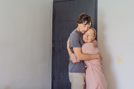 Man and woman hugging goodbye at the front door, sharing a tender emotional moment before parting ways. Concept of love, connection, farewell, relationships, and everyday intimate human emotions