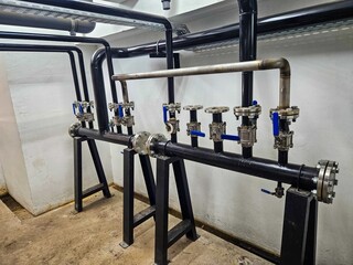Pipes and valves in an industrial setting, mounted on stands.