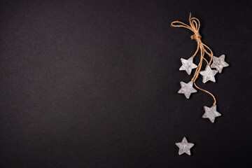 Flat lay decor with wooden stars and rope over black background, top view with copy space