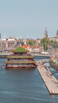Aerial cityscape panorama with the Basilica of Saint Nicholas in Amsterdam's Old Centre near the Central Station timelapse. People walking along the waterfront by boat station. Amsterdam, Netherlands