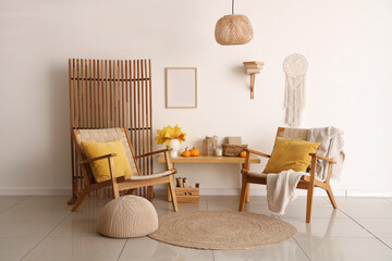 Interior of living room with autumn leaves, wooden bench and armchairs