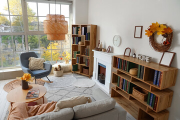 Fototapeta premium Interior of living room with autumn leaves, fireplace and bookshelves