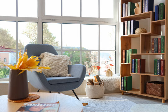 Interior of living room with autumn leaves, rocking armchair and bookshelf