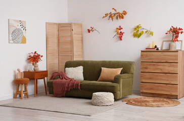 Interior of living room with autumn leaves, sofa and folding screen