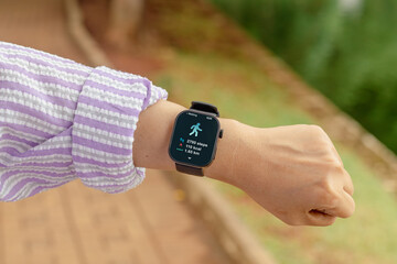 A woman counting her steps using her smart watch. Outdoors.