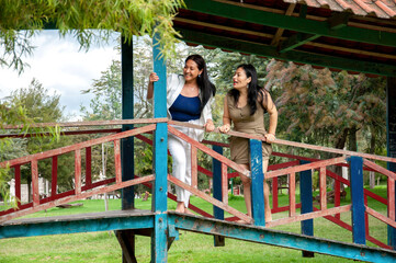 Women friends enjoying barefoot fun on park bridge