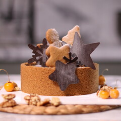 Delicious chocolate tart decorated with star and leaf cookies, walnuts, and cape gooseberries on a marble background. Perfect for holiday dessert, bakery presentation, or festive food photography