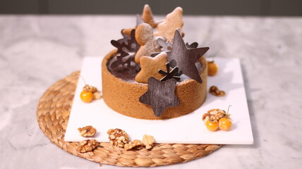 Delicious chocolate tart decorated with star and leaf cookies, walnuts, and cape gooseberries on a marble background. Perfect for holiday dessert, bakery presentation, or festive food photography