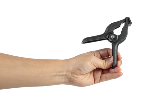 A studio shot of a black plastic spring clamp in hand isolated on a transparent background