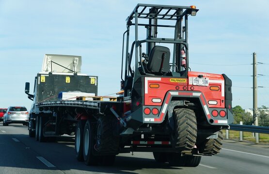 Lakeland, Florida, U.S - Nov 10, 2025 - The rear view of Flatbed truck transports construction materials with rear-mounted Palfinger FHS 55 forklift