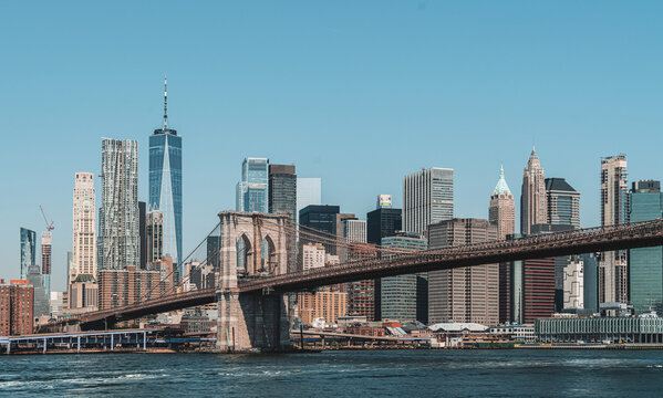 Brooklyn Bridge with Manhattan skyscrapers in daylight, realistic photo style, blue sky background. Concept of NYC architecture and urban skyline