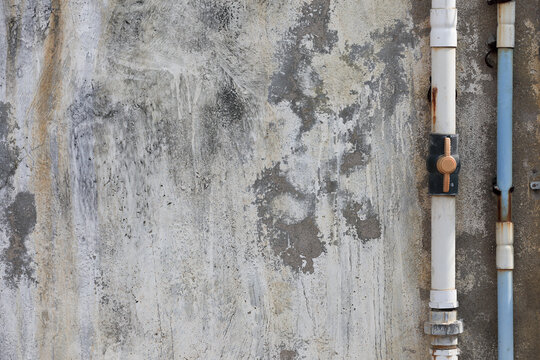 Old water pipes on Old weathered cement wall with crack