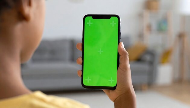 Person holds a smartphone with a green screen, indoors, blurred background