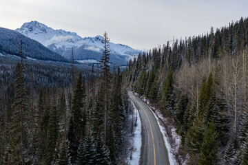 Snowy Mountain Road Through Dense Forest In British Columbia, Canada During Winter