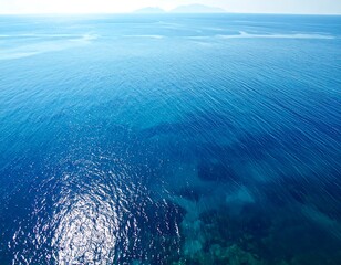 Deep blue ocean with subtle wave patterns and distant mountains on the horizon