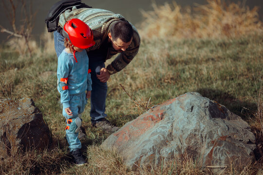Dad and Daughter Study a Rock on a Nature trip Together. Happy father and child exploring the environment and the wildlife - Powered by Adobe