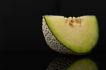 Vibrant Melon Slice on Reflective Black Background