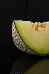 Vibrant Melon Slice on Reflective Black Background