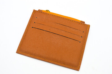 Overhead studio shot of a brown, Saffiano-textured card holder or small wallet with three card slots and a yellow zipper, isolated on a clean white background. Concept for finance, fashion, accessory.
