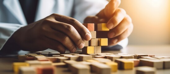 Hands building a tower with wooden blocks, symbolizing strategy and development.