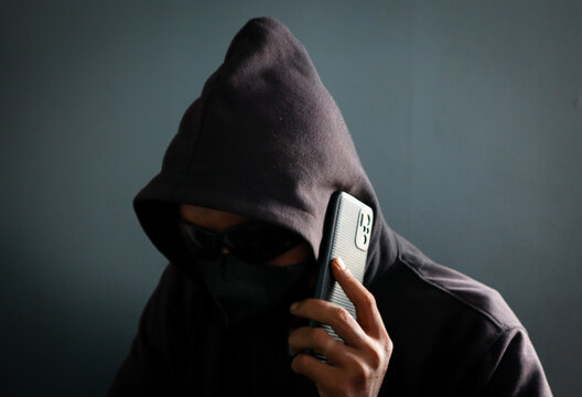 Phone Scammers, mysterious man with phone, cyber theft and fraud, mobile phone used for hacking, secret attacks on privacy.
