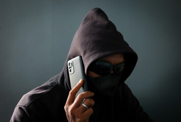 Phone Scammers, mysterious man with phone, cyber theft and fraud, mobile phone used for hacking, secret attacks on privacy. © eza