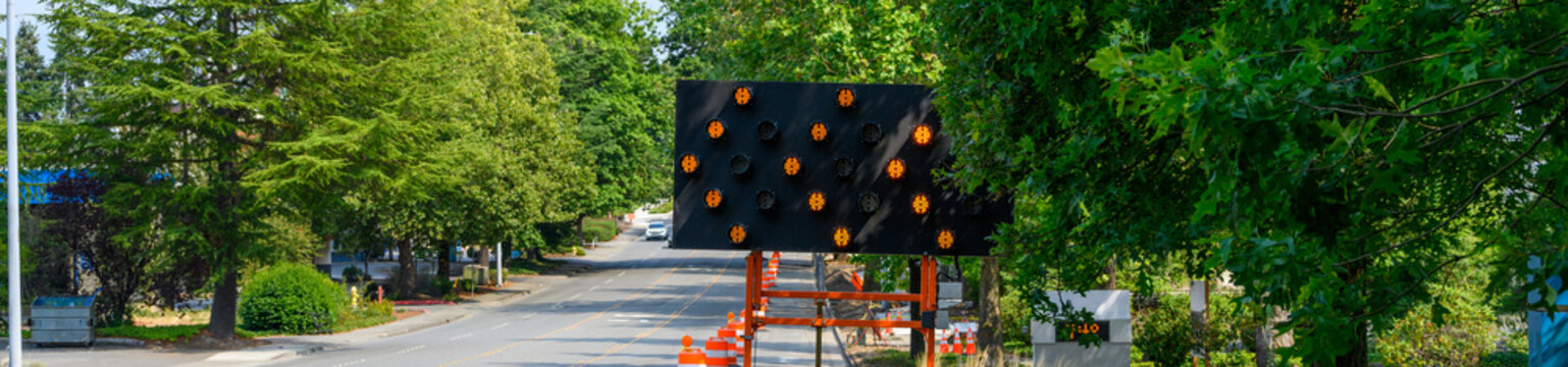 Arrow board used to direct traffic around temporary lane closure, move over lighted road sign with arrows, suburban traffic control
