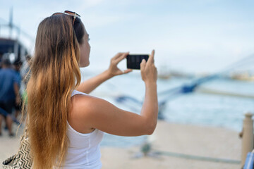 Woman taking a photo with her phone while traveling in El Nido, Philippines